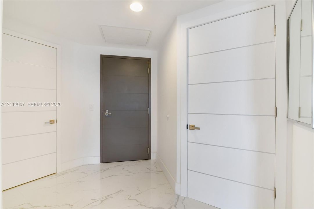 Entryway featuring polished stone-finish flooring with veining, recessed lighting, and contemporary interior doors with horizontal paneling and metallic lever hardware