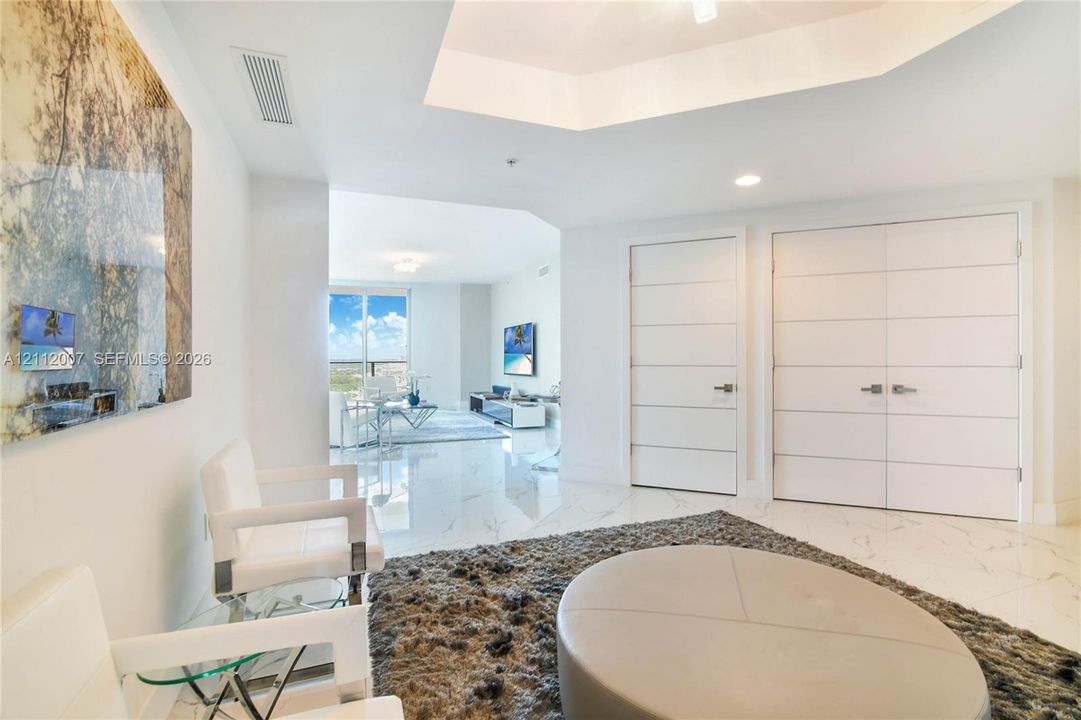 Interior space featuring a coffered ceiling, polished stone-finish flooring, and horizontal-paneled double doors
