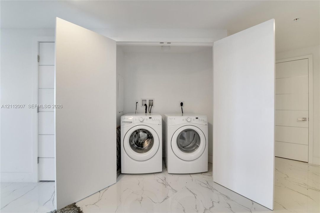 Laundry alcove featuring double-door entry and large-format tile flooring