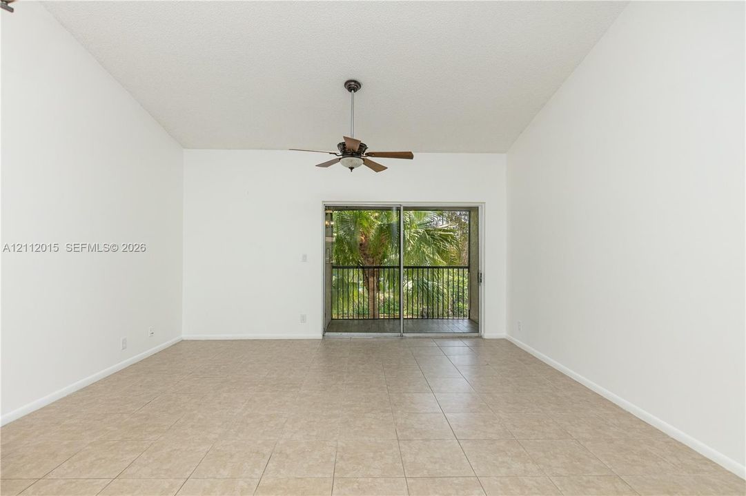 Vaulted ceilings, ceramic tile flooring, ceiling fan, and sliding glass doors with access to an outdoor balcony