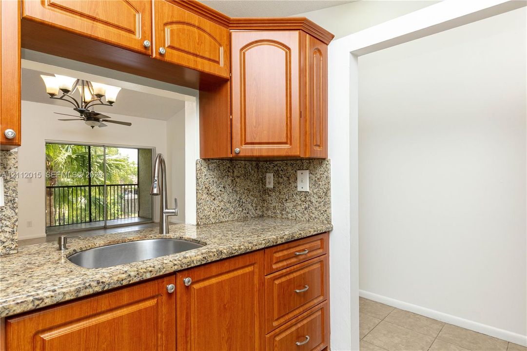 Kitchen featuring wood cabinetry, stone-finish countertops, stainless steel undermount sink, and high-arc pull-down faucet