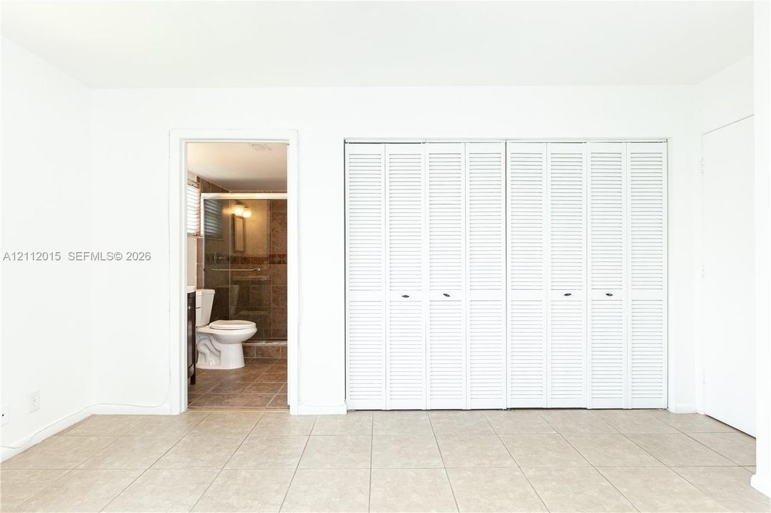 Room featuring tile flooring and white louvered bifold closet doors