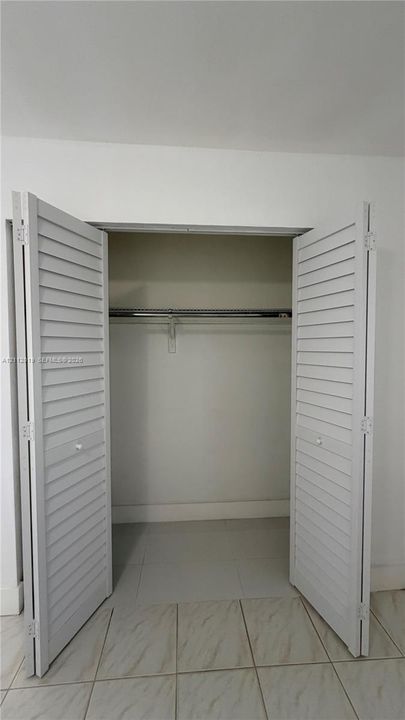 Closet featuring white louvered bifold doors and a built-in wire hanging rod