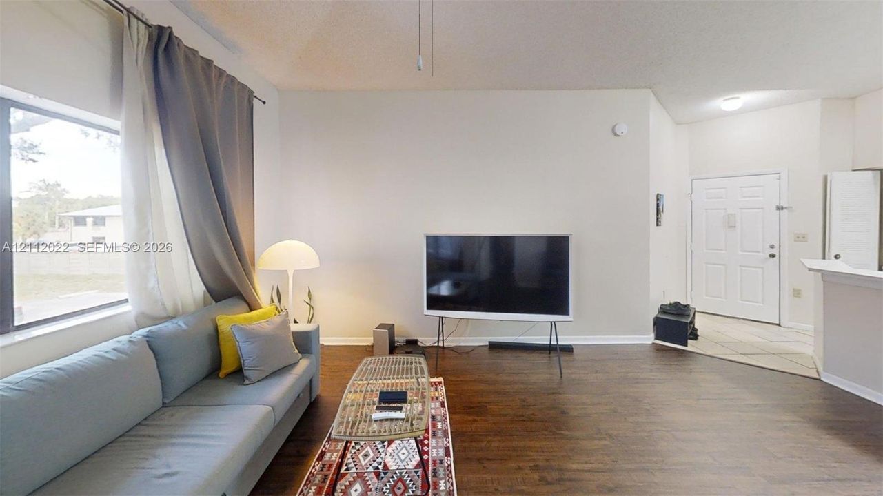 Living area featuring dark wood-finish flooring, a large picture window, and a ceiling fan