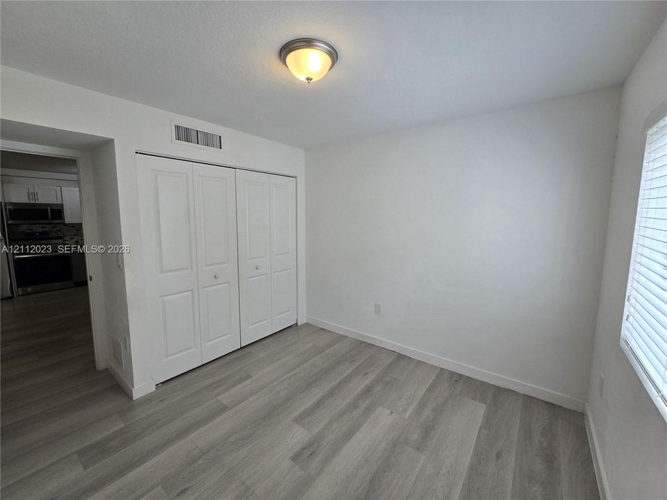 Neutral interior featuring wood-finish flooring, white walls, and a double-door closet