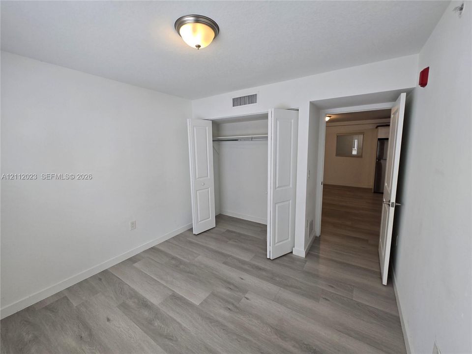 Wood-finish flooring, closet with paneled doors, and a flush-mount light fixture