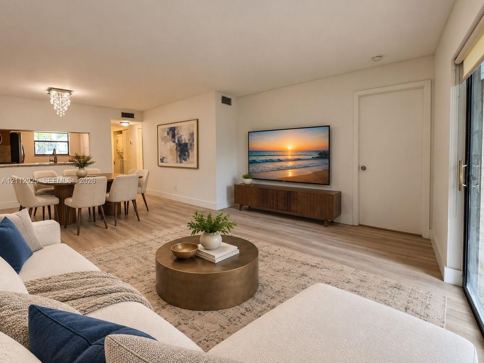 Open-concept interior featuring wood-finish flooring, a contemporary crystal chandelier, and a sliding glass door