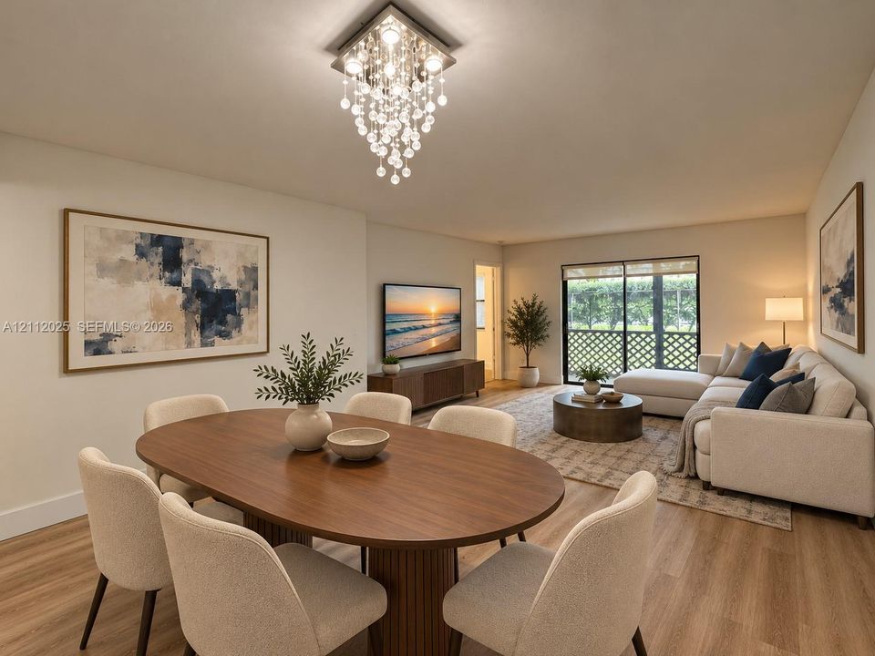Open-concept living space featuring wood-finish flooring, a tiered crystal chandelier, and sliding glass doors with decorative lattice screening
