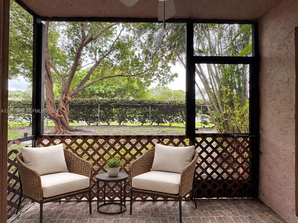Screened-in porch featuring a ceiling fan, brick-patterned flooring, lattice paneling, and metal framing