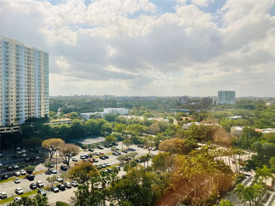 Elevated cityscape featuring expansive tree canopy, high-rise architectural silhouettes, and integrated surface parking