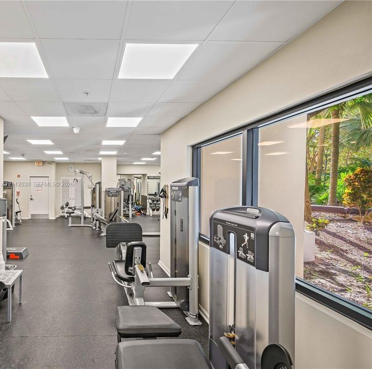 Fitness center featuring rubber flooring, recessed panel lighting, and large windows with exterior landscaping exposure