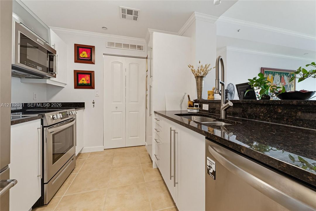 Kitchen featuring white cabinetry, dark stone-finish countertops, stainless steel appliances, a pull-down kitchen faucet, and tile flooring