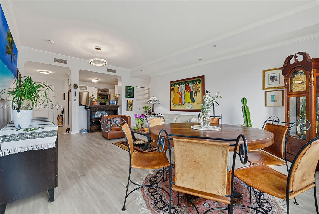 Open-concept interior featuring light wood-finish flooring, recessed lighting, crown molding, and a modern circular chandelier