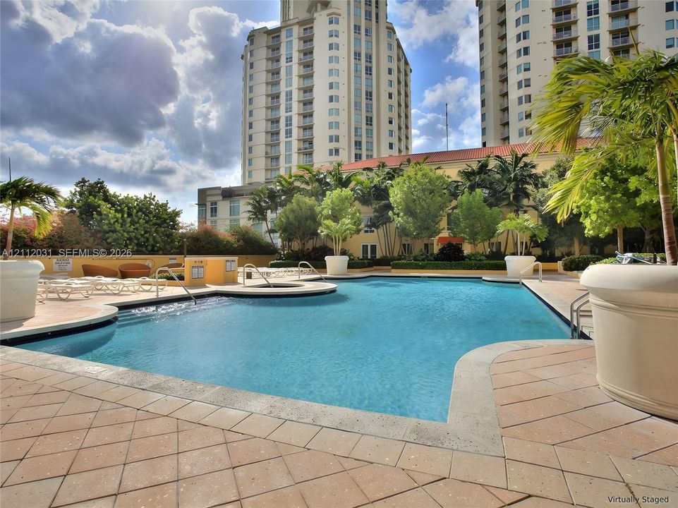 Swimming pool with integrated spa, tile decking, and large decorative planters