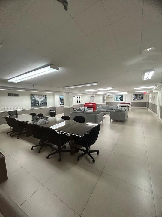 Expansive interior space featuring large-format tile flooring, linear fluorescent lighting, and two-tone wall finishes