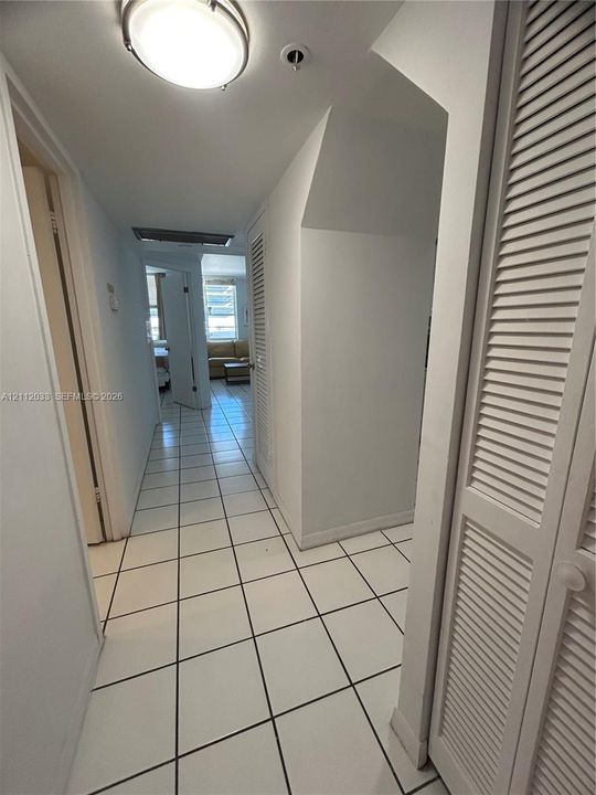 Ceramic tile flooring throughout with neutral-toned walls, flush-mount lighting, and white louvered-style closet doors