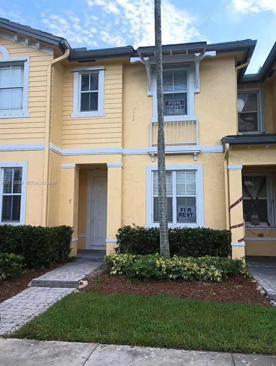 Exterior featuring stucco and lap siding, a metal balcony railing, double-hung windows, and a paved walkway