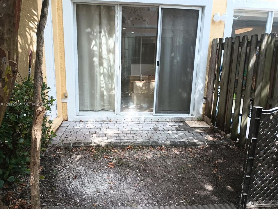 Paved brick patio featuring sliding glass doors and wood privacy fencing