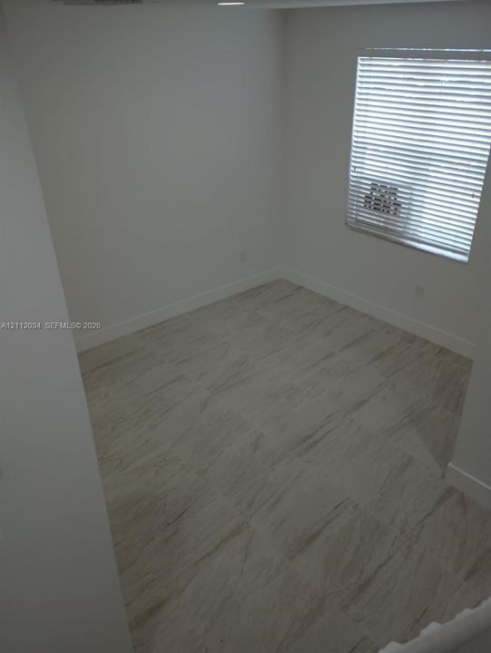 Neutral-toned large-format tile flooring and horizontal window blinds