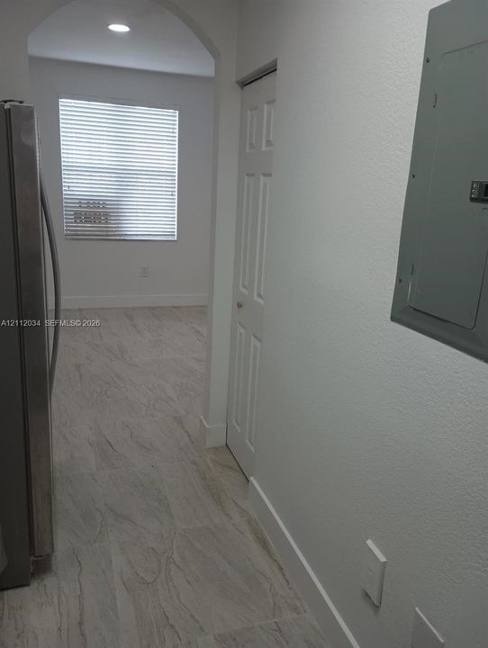 Arched entryway featuring neutral-toned tile flooring, recessed lighting, and a six-panel closet door