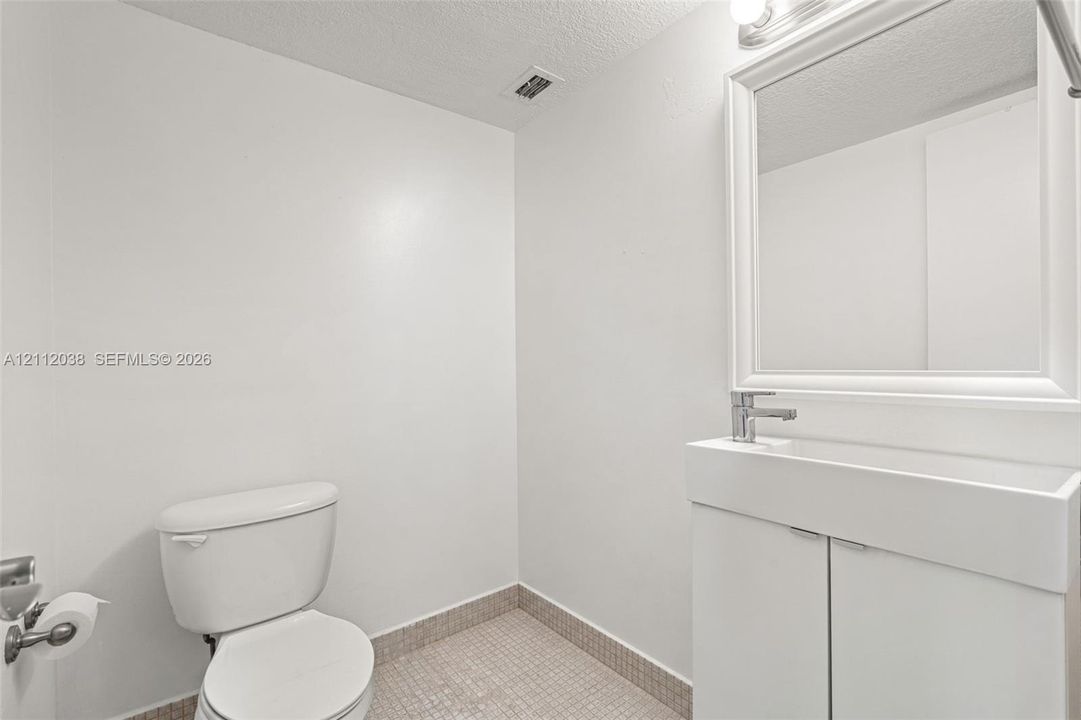 Half-Bathroom featuring a vanity with integrated sink, chrome faucet, framed wall-mounted mirror, and tiled flooring