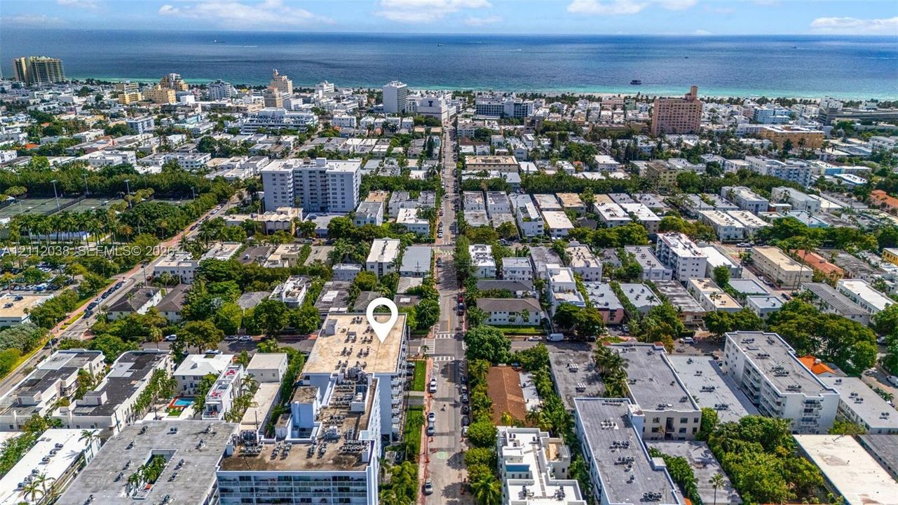 Aerial perspective of multi-story building featuring proximity to coastline and urban streetscape