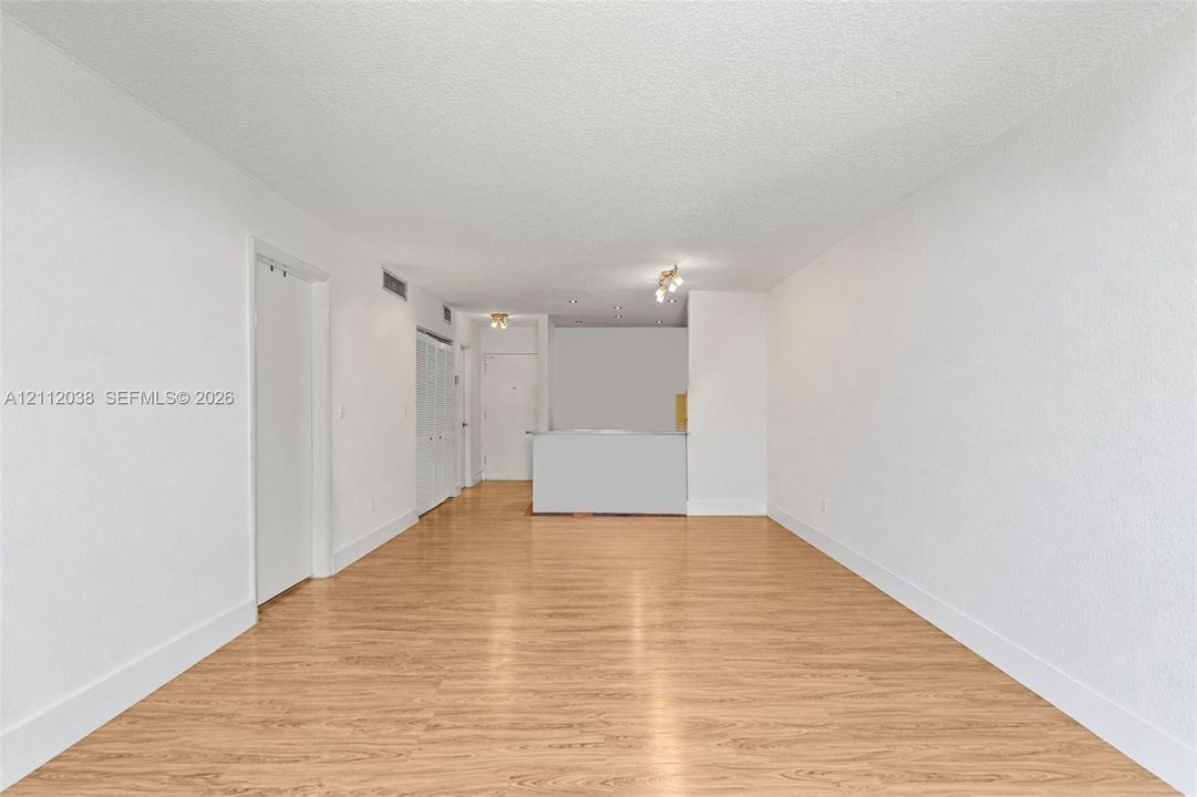 Open interior space featuring wood-finish flooring, textured ceiling, white walls, and built-in closet cabinetry