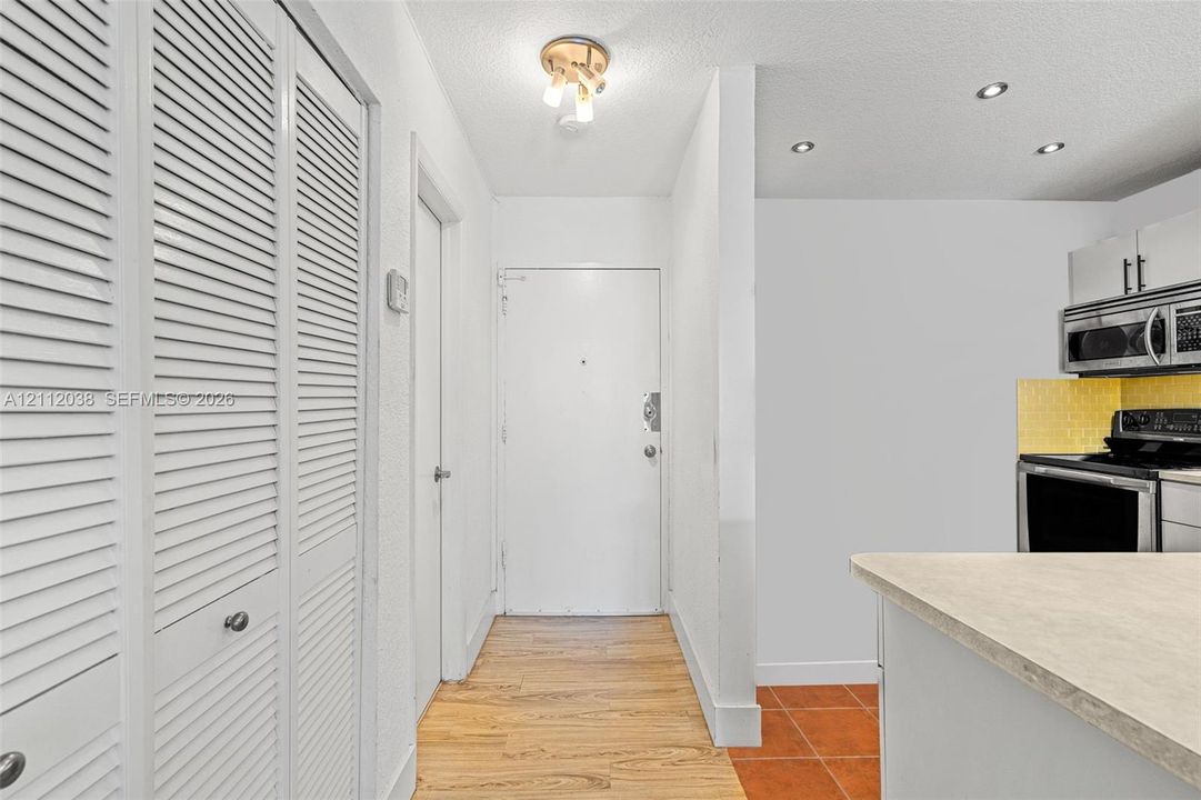 Entrance hall featuring wood-finish flooring, white louvered-door closets, a semi-flush mount light fixture, and recessed lighting