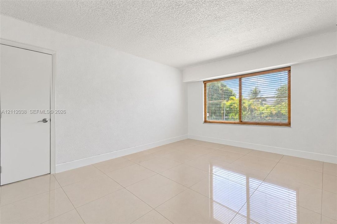 Bright interior space featuring polished tile flooring, smooth wall finishes, and a large window with natural light
