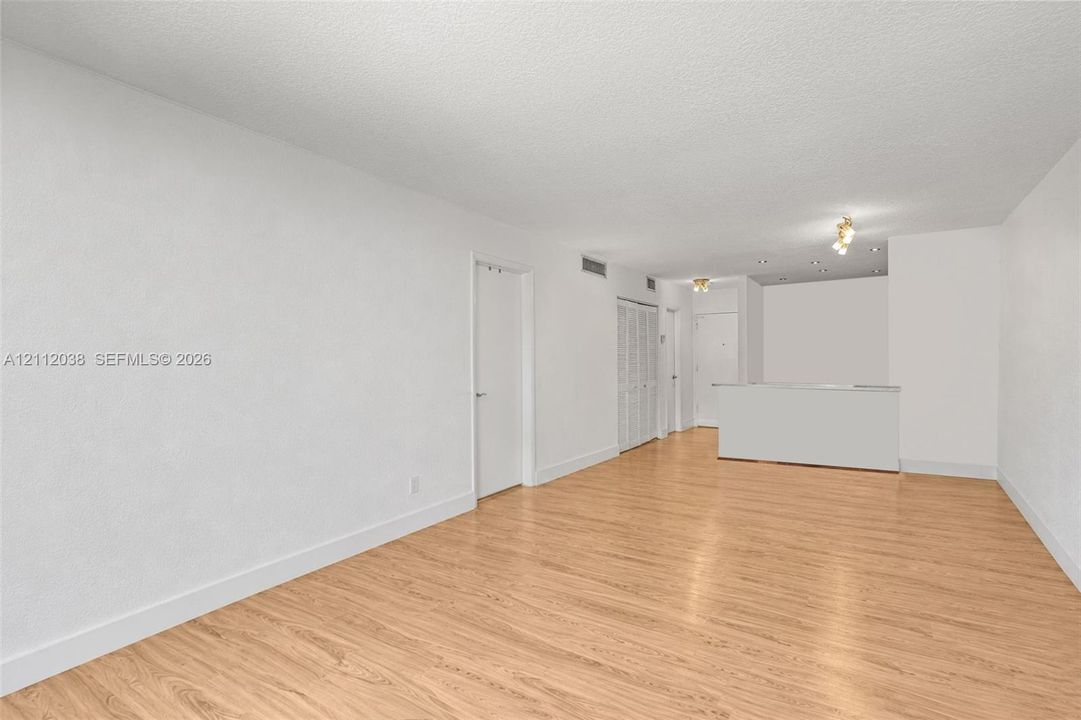 Interior space featuring wood-finish flooring, white walls, built-in cabinetry with louvered doors, and recessed ceiling lighting