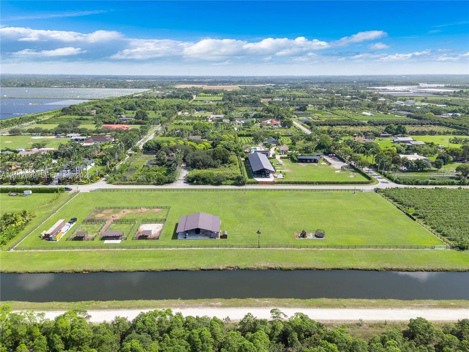Expansive acreage featuring a metal-roof barn, perimeter fencing, open pasture space, and a canal-front boundary
