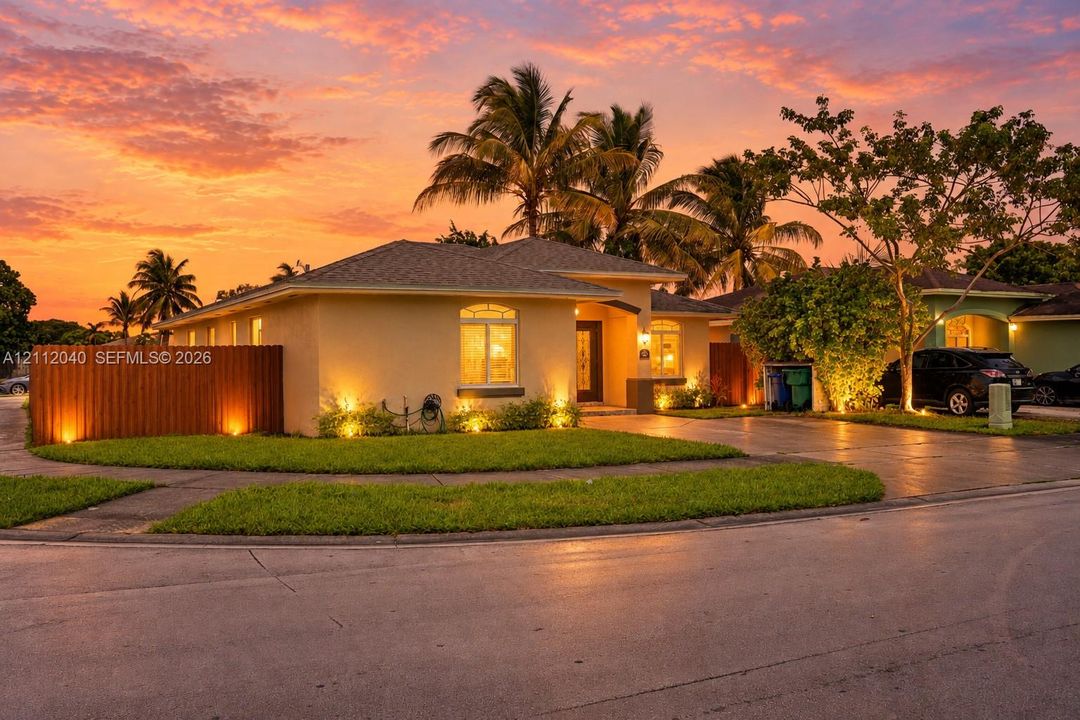 Single-story exterior featuring light-toned stucco siding, an asphalt shingle roof, a paved driveway, and an arched entryway