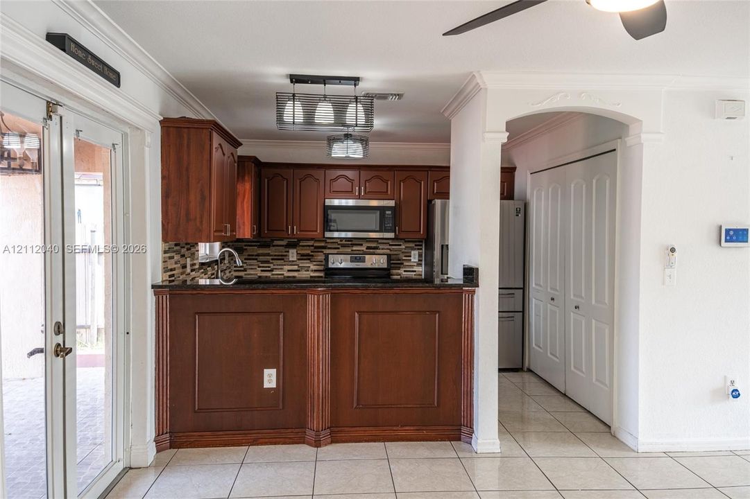 Kitchen featuring wood cabinetry, a decorative tile backsplash, stainless steel appliances, a raised breakfast bar, and tile flooring