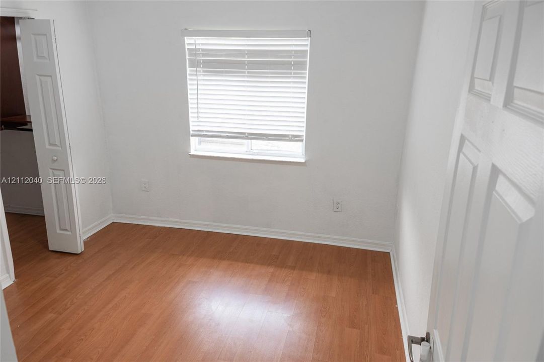Wood-finish flooring, horizontal window blinds, and paneled interior doors