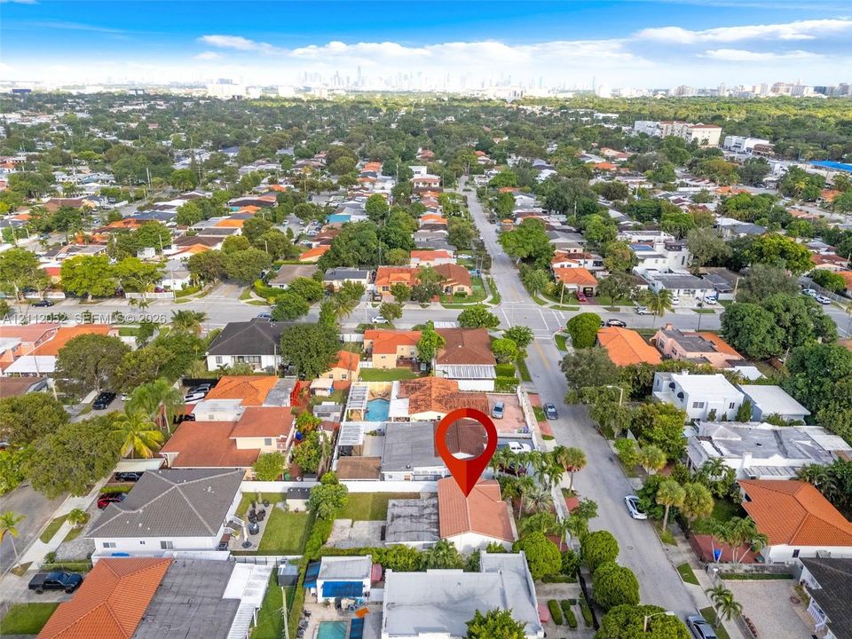 Aerial perspective showcasing a residential property with a tiled roof, situated within an established neighborhood featuring mature tree-lined streets