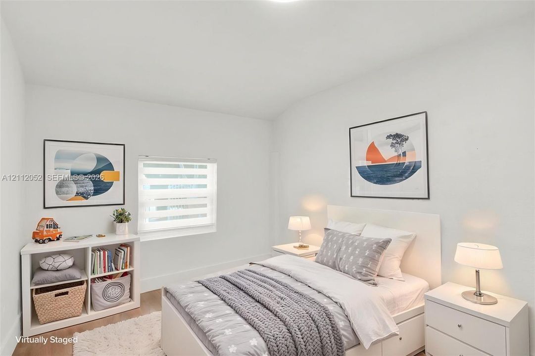 Neutral interior featuring smooth wall finishes, wood-finish flooring, and a dual-shade roller window treatment