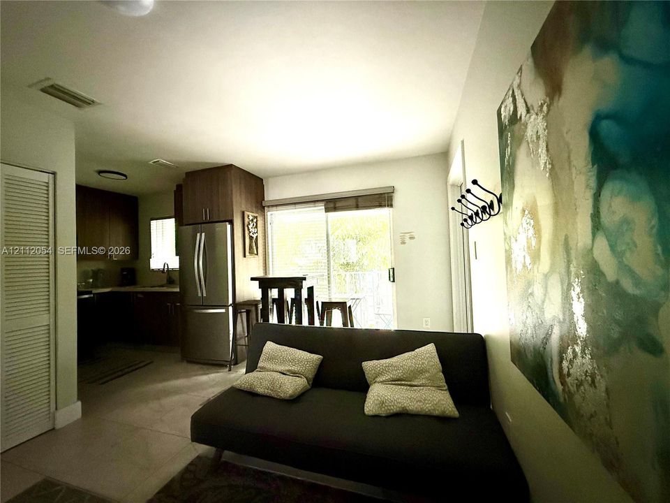 Kitchen featuring dark wood-finish cabinetry, stainless steel refrigerator, tile flooring, and a sliding glass door