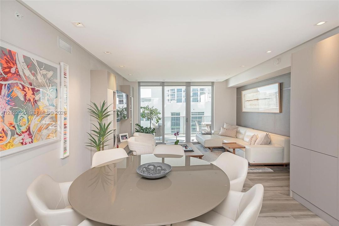 Open-concept living space featuring wood-finish flooring, recessed lighting, floor-to-ceiling windows, and custom built-in cabinetry