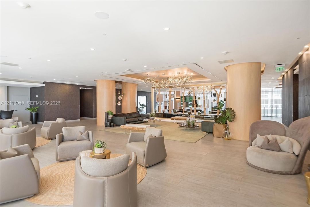 Open-concept interior featuring large cylindrical structural columns, recessed ceiling lighting, textured wall finishes, and wood-finish tile flooring