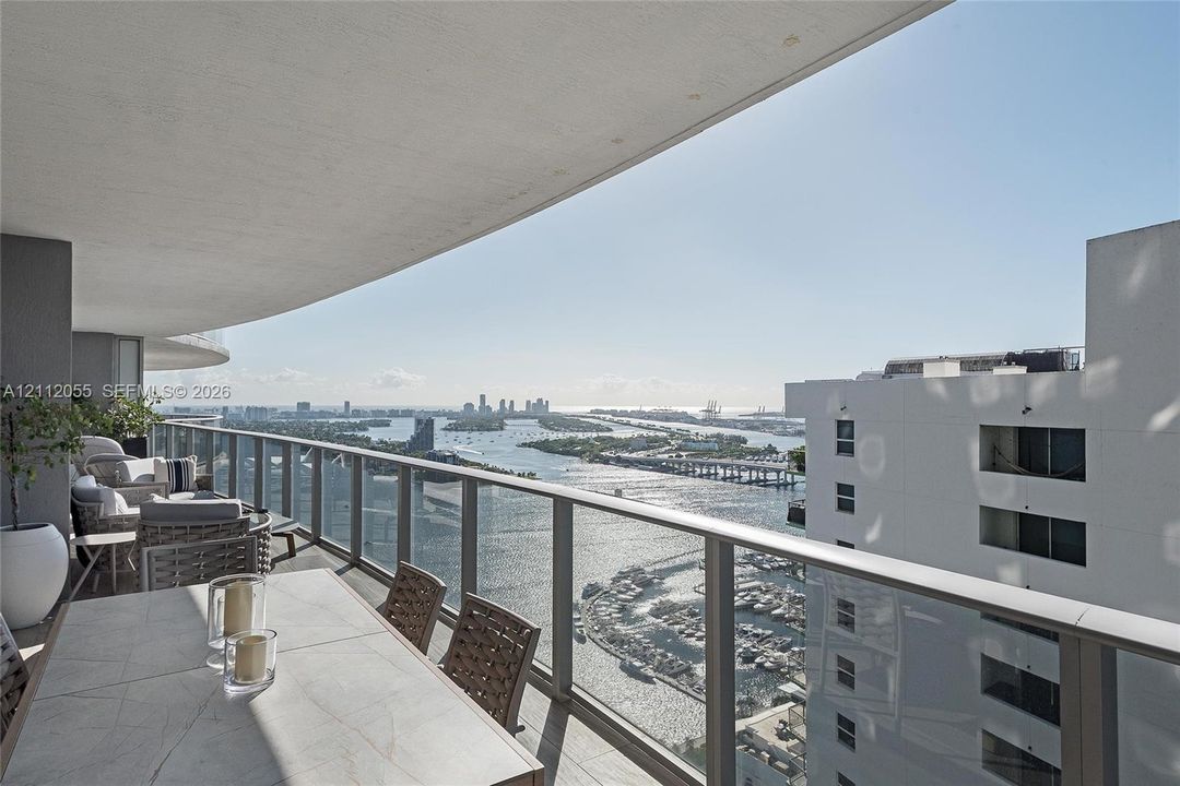 Covered balcony featuring a glass-panel railing, tile flooring, and a stone-topped built-in surface