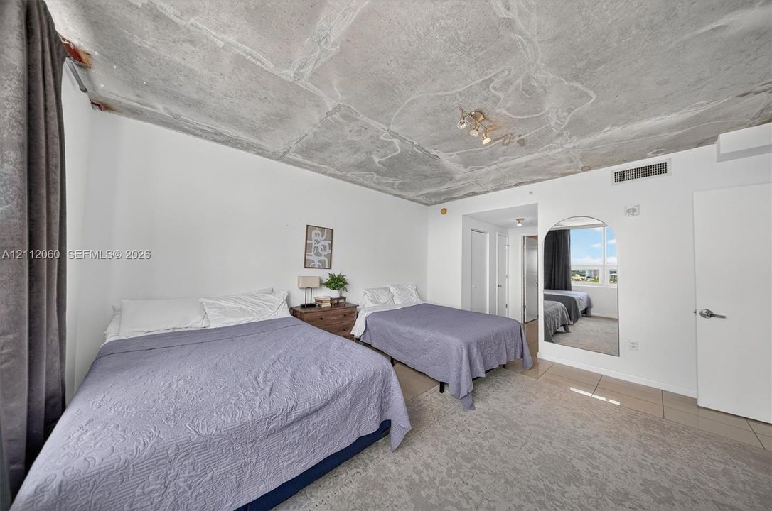 Exposed concrete ceiling, arched mirror, and tile flooring