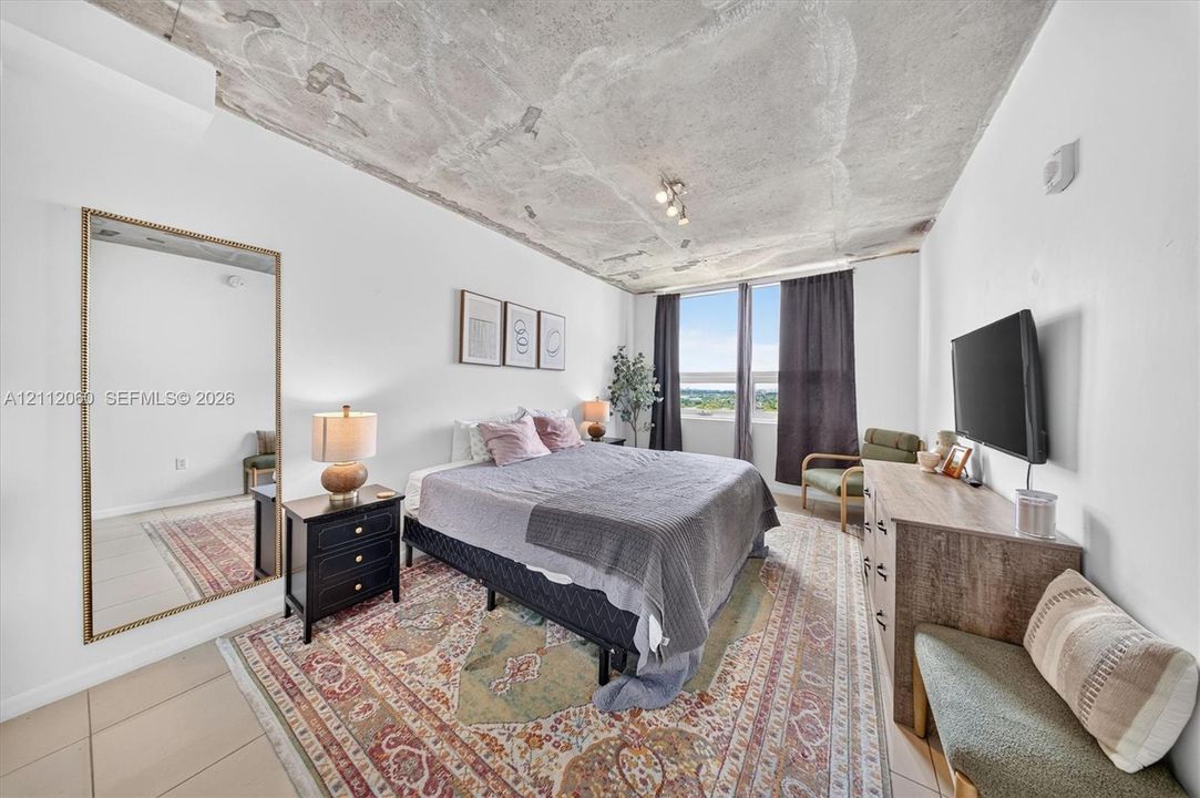 Exposed concrete ceiling, large window with natural light, and tile flooring
