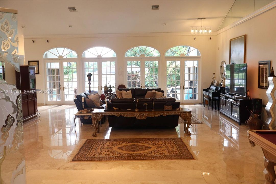 Polished stone flooring, high ceilings, and four sets of arched French glass doors