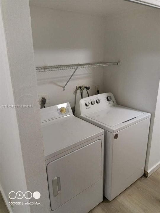 Laundry alcove featuring wood-finish flooring and a wire shelving unit
