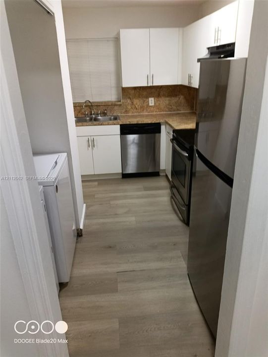 Kitchen featuring white cabinetry, wood-finish flooring, stainless steel appliances, and a dual-basin sink with a countertop