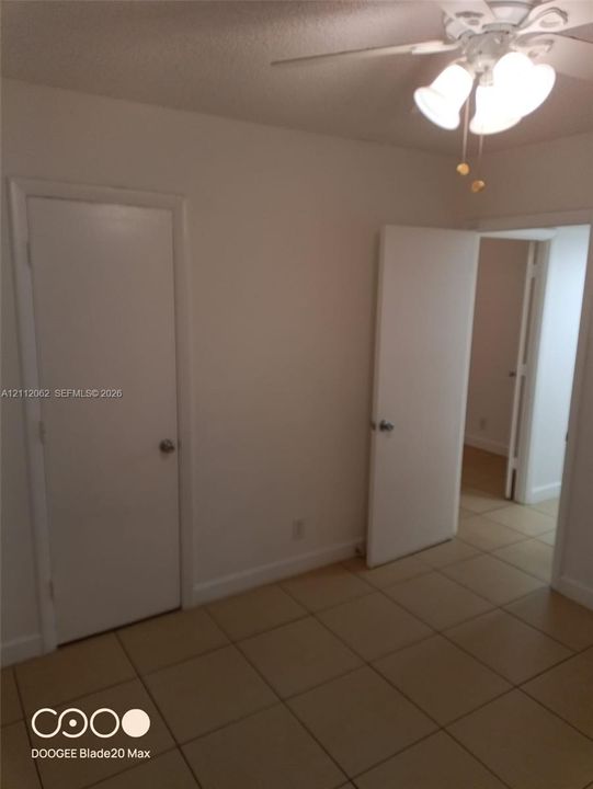 Neutral-toned tile flooring, white-painted interior doors, and a ceiling-mounted light fixture with frosted glass shades