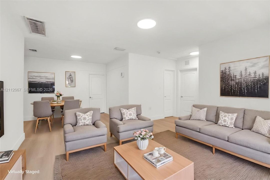 Open-concept interior featuring light-toned wood-finish flooring, recessed ceiling lighting, and multi-panel interior doors