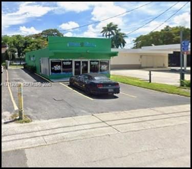 Commercial storefront featuring a flat-roof architectural style, expansive glass display windows, and an asphalt-paved dedicated parking area