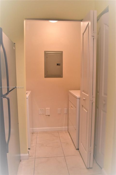 Dedicated alcove featuring tile flooring and bi-fold door access to laundry hookups