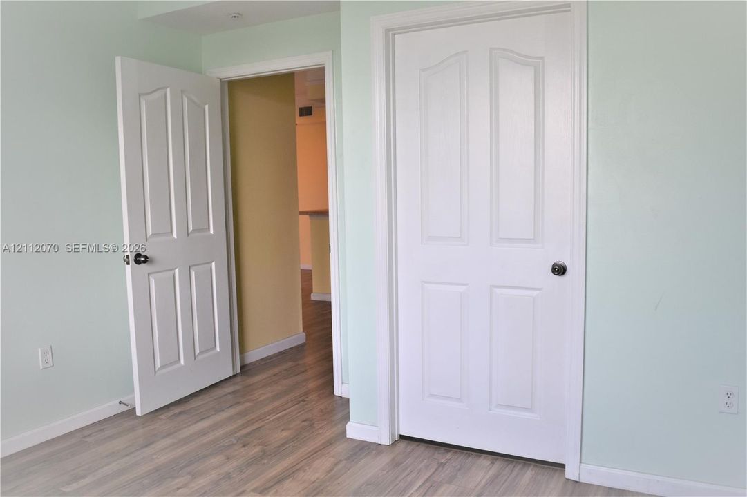 Interior space featuring wood-finish flooring and two white four-panel interior doors with black hardware